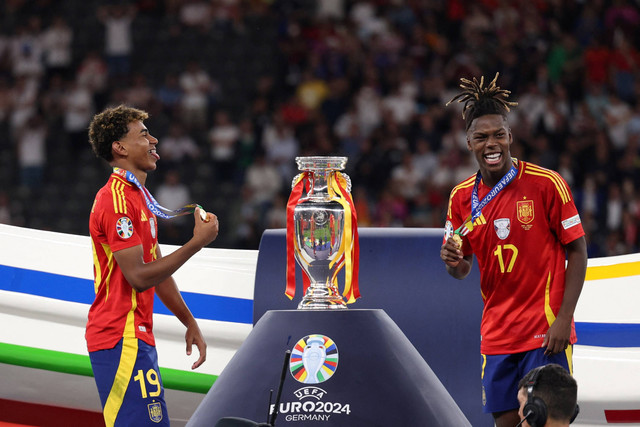 Pemain Timnas Spanyol Lamine Yamal dan Nico Williams merayakan juara Piala Eropa 2024 di Olympiastadion, Berlin, Jerman, Minggu (14/7/2024). Foto: Adrian DENNIS / AFP