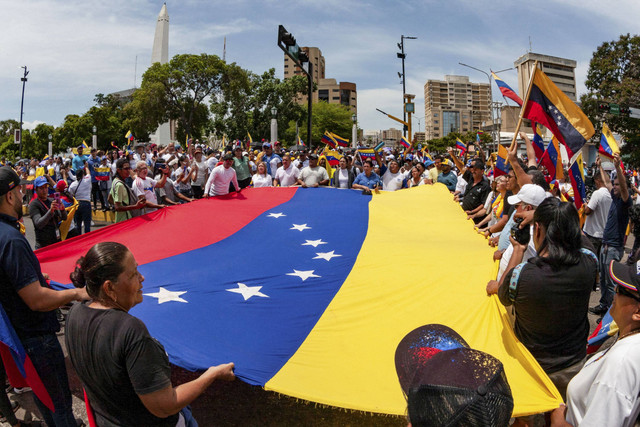Orang-orang membawa bendera nasional Venezuela untuk memprotes hasil pemilu yang memberikan masa jabatan ketiga bagi Presiden Venezuela Nicolas Maduro, di Maracaibo, Venezuela, Rabu (31/7/2024). Foto: Isaac Urrutia/REUTERS