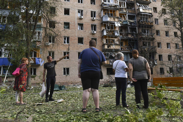 Penghuni gedung apartemen yang rusak setelah ditembaki oleh pihak Ukraina berdiri di dekat gedung tersebut di Kursk, Rusia, Minggu (11/8/2024). Foto: AP Photo