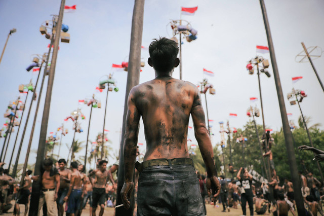 Peserta lomba panjat pinang berusaha mencapai puncak tiang untuk mengambil hadiah saat digelar lomba panjat pinang di Ancol, Jakarta, Sabtu (17/8/2024). Foto: Jamal Ramadhan/kumparan