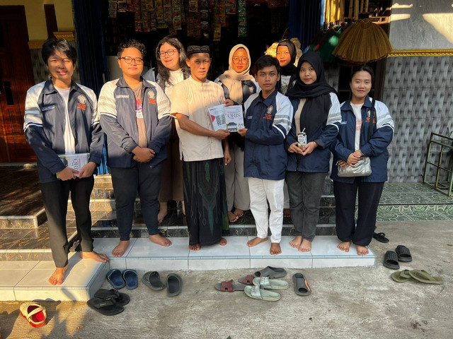 Pemberian print QRIS dari salah satu UMKM serta pemberian buku mengenai QRIS (Sumber: Pribadi)