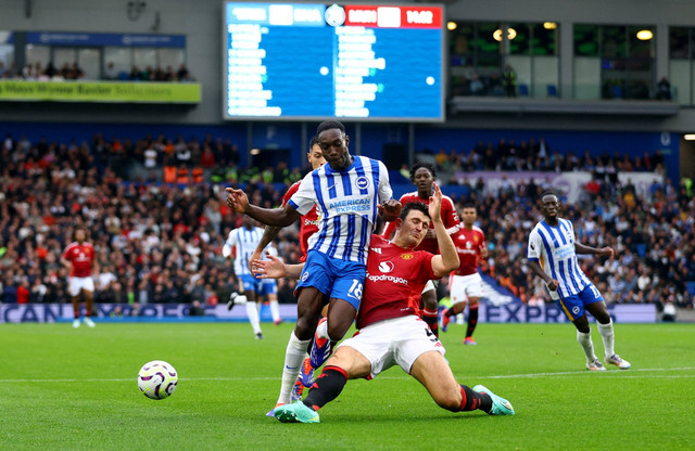 Pemain Brighton Hove Albion Danny Welbeck berusaha melewati pemain Manchester United Harry Maguire pada pekan kedua Liga Inggris di The American Express Community Stadium,  Brighton, Inggris, Sabtu (24/8/2024). Foto: Matthew Childs/Reuters