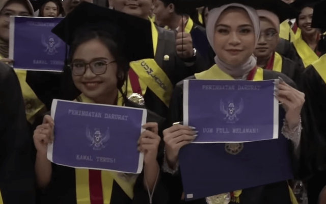 Wisudawan UGM mengangkat poster Peringatan Darurat dalam wisuda hari kedua, Kamis (29/8/2024). Foto: YouTube/UGM