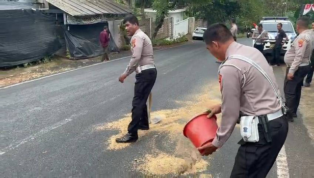 Anggota Satlantas Polresta Bandar Lampung saat menyiram tumpahan diduga solar menggunakan pasir. | Foto: Istimewa