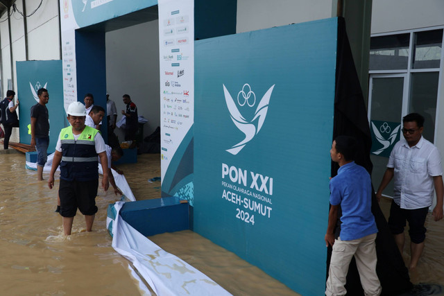 Sejumlah pekerja berusaha menghalau aliran air agar tidak masuk ke venue lapangan tembak indoor SR 50 meter PON XXI Aceh-Sumut 2024 di Lapangan Tembak Rindam IM Mata Ie, Aceh Besar, Aceh, Selasa (17/9/2024). Foto: Arnas Padda/ANTARA FOTO