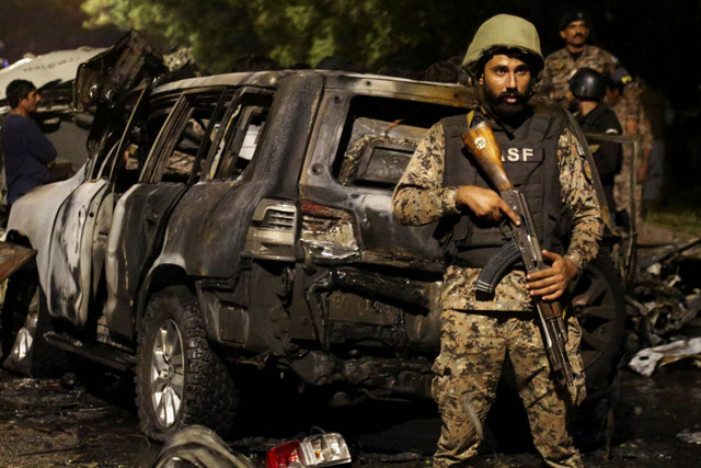 Anggota Pasukan Keamanan Bandara ASF berjaga di dekat reruntuhan kendaraan setelah ledakan di dekat Bandara Internasional Jinnah di Karachi, Pakistan, Minggu (6/10/2024). Foto: Shakil Adil/REUTERS