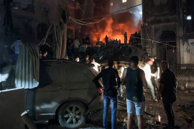 Anggota pertahanan sipil Lebanon dan warga lainnya memeriksa lokasi serangan udara Israel di wilayah Basta, Beirut, pada 10 Oktober 2024. Foto: AFP
