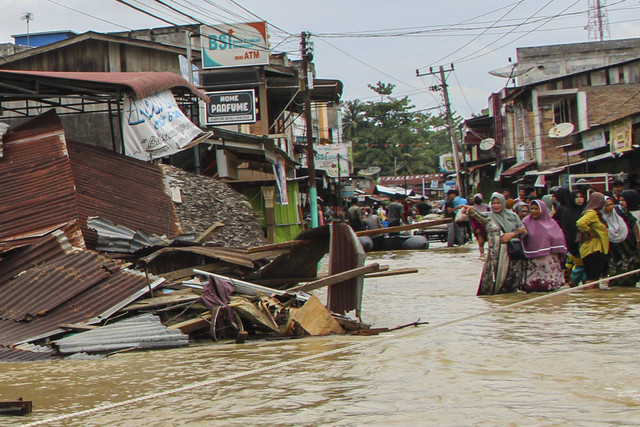 Sejumlah warga melintasi air yang menggenangi jalan di Desa Pekan Seruway, Kabupaten Aceh Tamiang, Aceh, Rabu (16/10/2024). Foto: Dede Harison/ANTARA FOTO