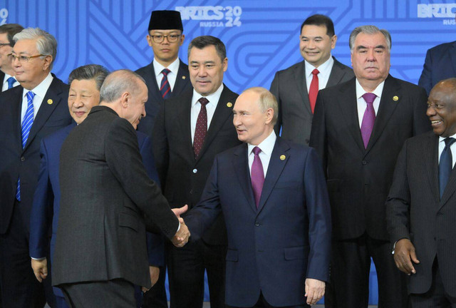 Presiden Rusia V. Putin bersalaman dengan Presiden Turki Erdogan di KTT BRICS di Kazan, 24 Oktober 2024. Tampak Menlu Sugiono berpeci. Foto: Grigory Sysoev/Photohost agency brics-russia2024.ru