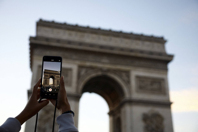 Pengunjung foto Arc de Triomphe saat matahari terbenam di Paris, Prancis, Kamis (24/10/2024). Foto: Sarah Meyssonnier/Reuters