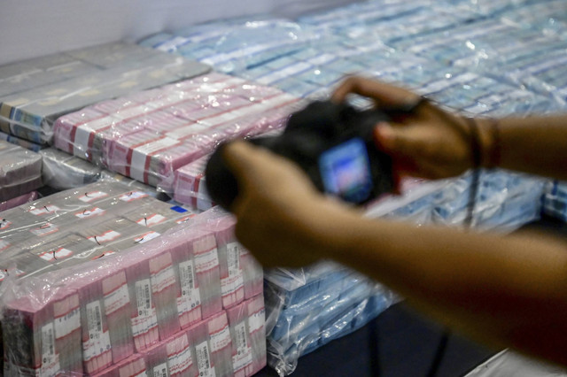 Wartawan memotret uang tunai barang bukti kasus judi online, di Bareskrim Polri, Sabtu (2/11/2024). Foto: Rivan Awal Lingga/ANTARA FOTO
