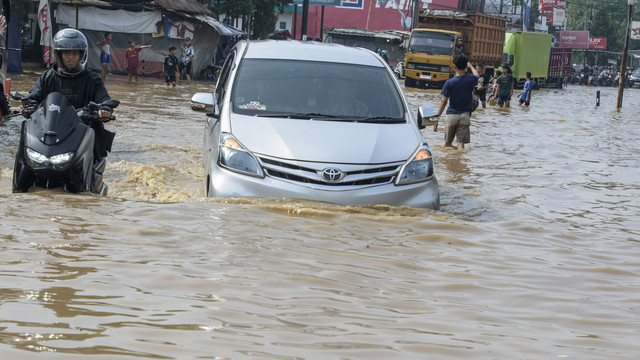 Pengendara motor dan mobil berusaha melintasi banjir di Dayeuhkolot, Kabupaten Bandung, Jawa Barat, Jumat (22/11/2024). Foto: ANTARA FOTO/Novrian Arbi