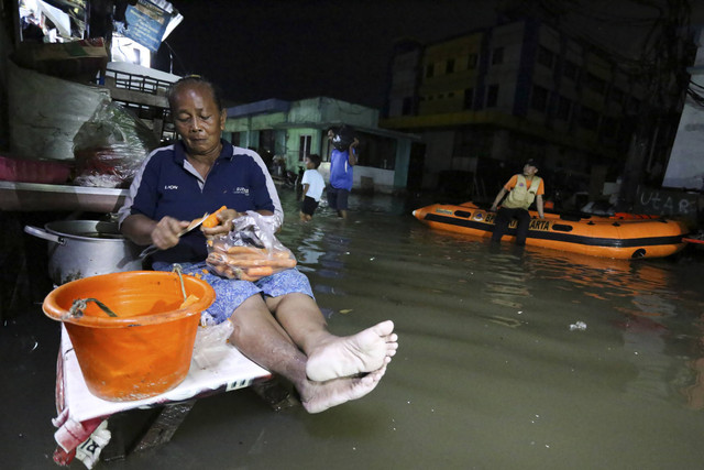 Seorang warga mengupas sayuran saat banjir rob di kawasan Muara Angke, Jakarta, Senin (18/11/2024). Foto: Alif Bintang/ANTARA FOTO