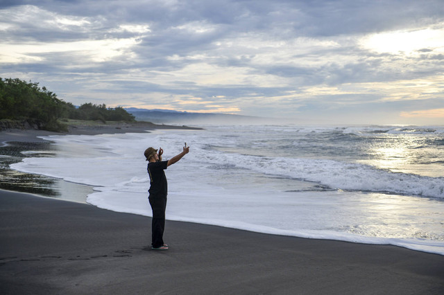 Wisatawan berfoto di kawasan wisata Pantai Cemara Cipanglay, Kecamatan Cidaun, Kabupaten Cianjur, Jawa Barat, Sabtu (30/11/2024). Foto: Raisan Al Farisi/ANTARA FOTO