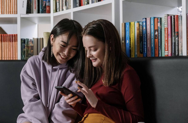 Foto oleh Cottonbro Studio dari Pexels Photo by https://www.pexels.com/photo/a-girl-in-red-sweater-holding-her-phone-while-talking-to-her-friend-6214560/