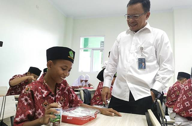 Kepala Kanwil Bulog SulutGo, Ermin Tora, saat berbincang dengan siswa yang ikut dalam program makan bergizi gratis di Kota Manado, Sulawesi Utara.