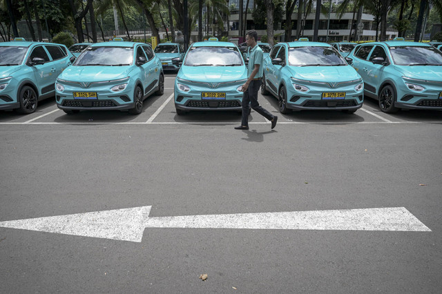 Seorang pengemudi berjalan di depan taksi Xanh SM yang terparkir saat peluncuran di Jakarta, Rabu (18/12/2024). Foto: Fauzan/ANTARA FOTO