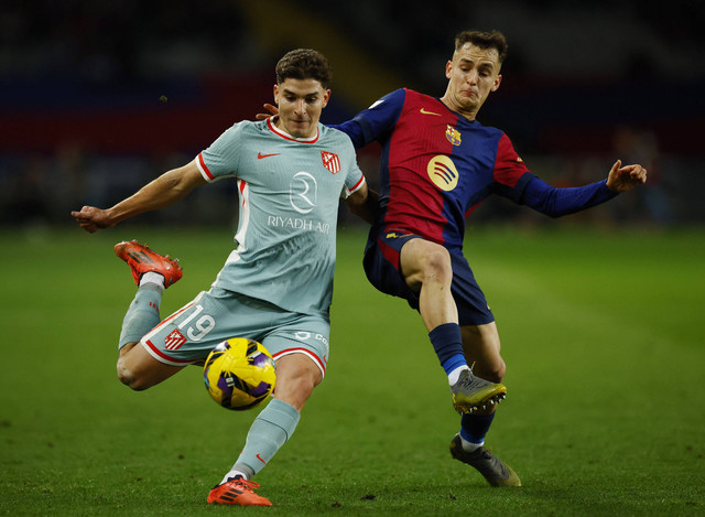 Pemain Atletico Madrid Julian Alvarez beraksi dengan pemain FC Barcelona Marc Casado pada pertandingan Liga Spanyol antara Barcelona melawan Atletico Madrid di Estadi Olimpic Lluis Companys, Barcelona, Spanyol, Minggu (22/12/2024) dini hari WIB. Foto: Albert Gea/REUTERS