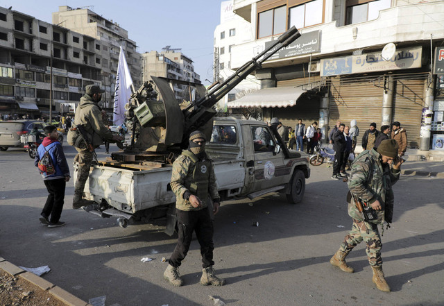 Dua pejuang Suriah melakukan patroli usai 14 Polisi tewas dalam penyergapan di Homas, Suriah, Kamis (26/12/2024). Foto: Khalil Ashawi/Reuters