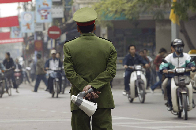 Seorang polisi berjaga di sebuah jalan yang sibuk di pusat kota Hanoi, Vietnam (2/12/2003). Foto: Hoang Dinh Nam/AFP