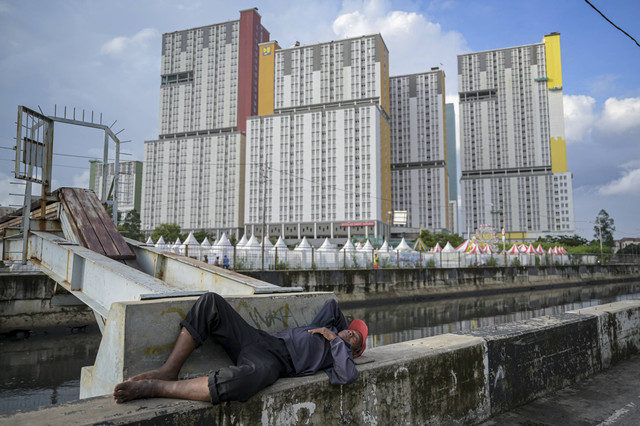 Seorang warga beristirahat di dekat Wisma Atlet Kemayoran, Jakarta, Senin (13/1/2025). Foto: Fauzan/ANTARA FOTO