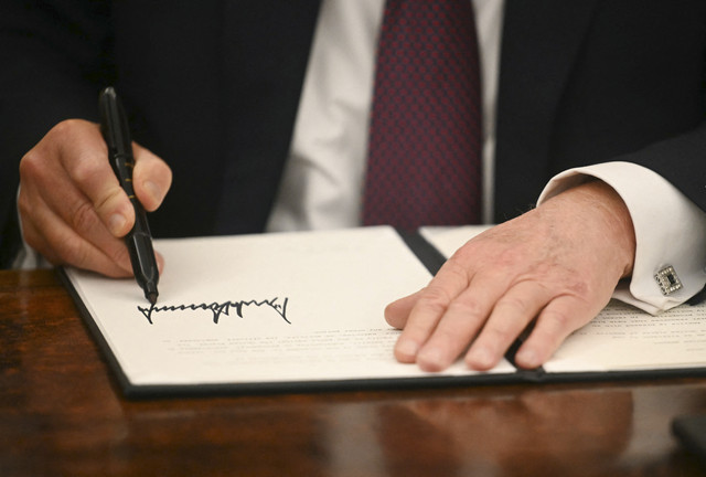 Presiden AS Donald Trump menandatangani perintah eksekutif di Ruang Oval Gedung Putih di Washington DC, Amerika Serikat, Selasa (21/1/2025). Foto: Jim Watson/AFP