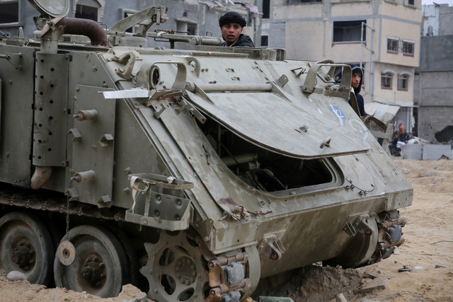 Warga Palestina melihat kendaraan militer Israel yang rusak menyusul gencatan senjata antara Israel dan Hamas di Rafah, Jalur Gaza selatan, Rabu (22/1/2025). Foto: Hatem Khaled/REUTERS
