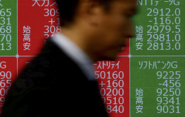 Seorang pria berjalan melewati papan kutipan saham yang menunjukkan harga saham SoftBank Group di Bursa Efek Tokyo di luar pialang di Tokyo, Jepang, Selasa (28/1/2025). Foto: Issei Kato/REUTERS