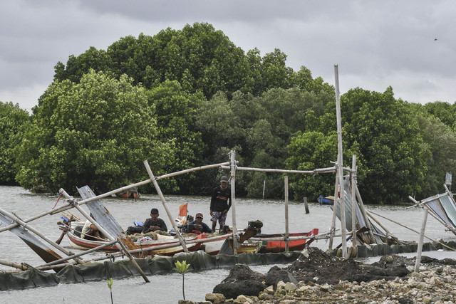 Nelayan menambatkan perahunya di samping pagar laut di Pesisir Tarumajaya, Desa Segarajaya, Kabupaten Bekasi, Jawa Barat, Kamis (30/1/2025). Foto: Fakhri Hermansyah/ANTARA FOTO
