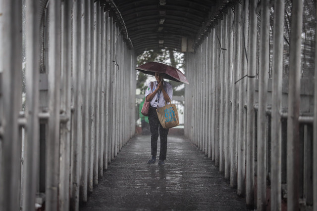 Warga berjalan di jembatan penyeberangan orang (JPO) saat hujan mengguyur di kawasan Jalan Gatot Subroto, Jakarta, Senin (17/2/2025). Foto: Jamal Ramadhan/kumparan
