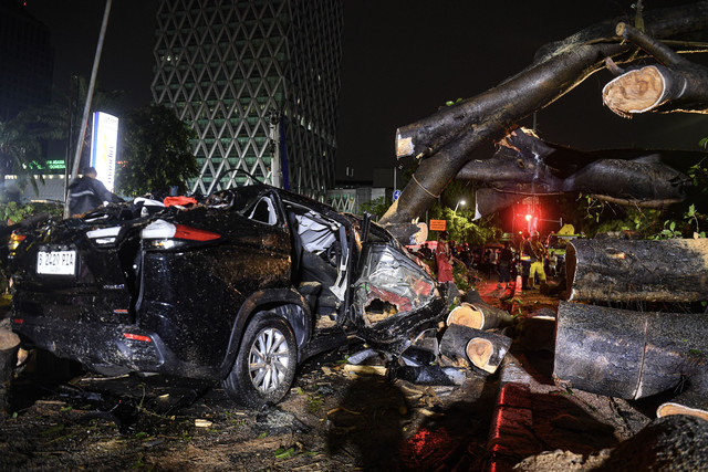 Petugas melintas di samping mobil yang tertimpa pohon tumbang setelah hujan deras disertai angin kencang di kawasan Kebon Sirih, Jakara Pusat, Selasa (18/3/2025) dini hari. Foto: ANTARA FOTO/Muhammad Adimaja