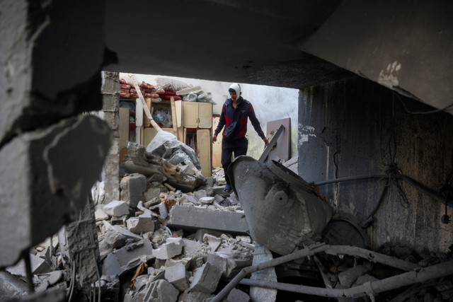 Warga Palestina yang terluka mencari barang-barang yang bisa diselamatkan di antara puing-puing yang hancur Foto: Eyad BABA / AFP