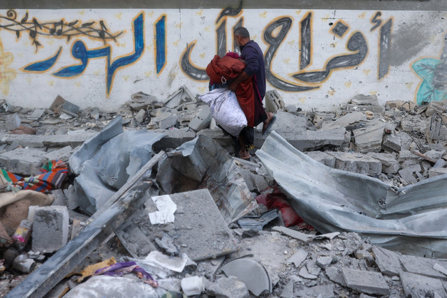 Warga Palestina membawa barang-barang yang diselamatkan dari puing-puing rumahnya yang hancur akibat serangan Israel di kamp pengungsi Nuseirat, Jalur Gaza bagian tengah, Selasa (18/3/2025). Foto: Eyad BABA / AFP