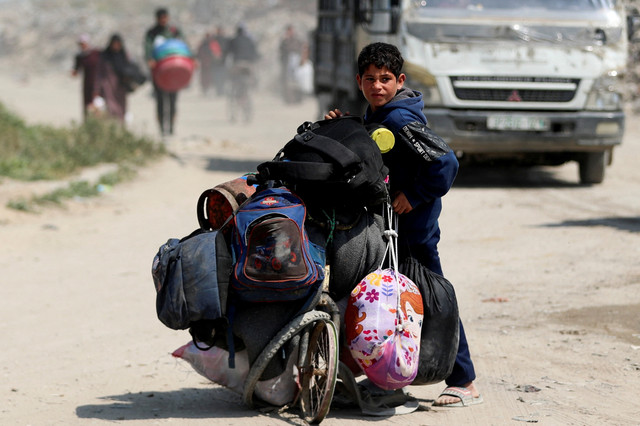 Seorang anak Palestina membawa barang-barang saat mengungsi dari rumah mereka setelah serangan udara Israel di Jalur Gaza, Selasa (18/3/2025). Foto: Mahmoud Issa/REUTERS