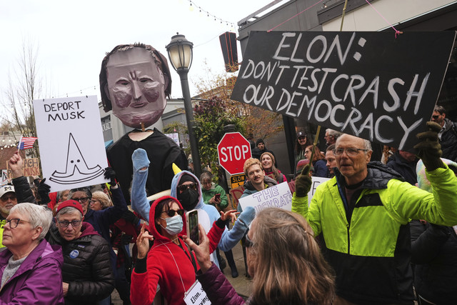 Orang-orang melambaikan tangan dan melambaikan bendera dalam sebuah protes menentang Tesla dan Elon Musk di luar ruang pamer Tesla di University District, Seattle, Sabtu (29/3/2025).  Foto: Lindsey Wasson/AP PHOTO