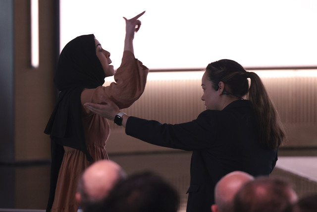 Seorang demonstran pro-Palestina, Ibtihal Aboussad, dikawal oleh petugas keamanan saat mereka mengganggu CEO AI Microsoft Mustafa Suleyman saat presentasi tentang asisten AI perusahaan, Copilot di markas besar Microsoft, Jumat (4/4/2025). Foto: Jason Redmond/REUTERS
