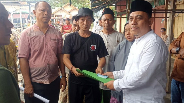Bupati Bolmong, Yusra Alhabsyi (baju putih) menyerahkan dokumen administrasi kependudukan kepada korban kebakaran Pasar Lolak, sebagai pengganti dokumen yang terbakar.