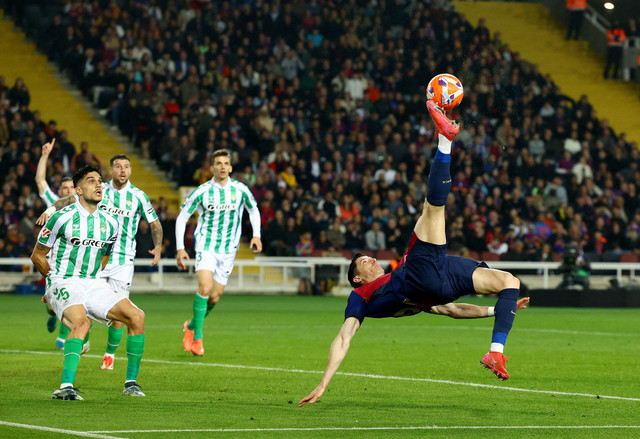 Aksi Robert Lewandowski salto saat laga FC Barcelona vs Real Betis dalam pekan ke-30 Liga Spanyol 2024/25 di Stadion Olimpic Lluis Companys, Minggu (6/4) dini hari WIB. Foto: REUTERS/Albert Gea
