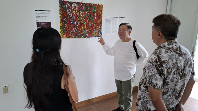 Seniman Sam Sianata menjelaskan tentang lukisannya yang sedang dipamerkan di Bali. (foto: istimewa)