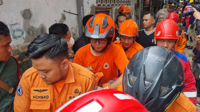 Petugas mengevakusi korban yang terkena tembok balkon runtuh di bangunan rumah samping Pasar Kupang Gunung, Kecamatan Sawahan, Surabaya, Selasa (8/4/2025). Foto: Farusma Okta Verdian/kumparan