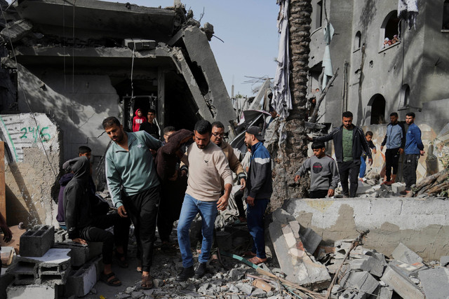 Warga Palestina memeriksa lokasi yang terkena serangan Israel di Deir al-Balah, Jalur Gaza, Senin (7/4/2025). Foto: Abdel Kareem Hana/AP PHOTO