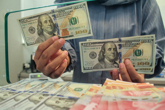 Petugas menunjukan uang pecahan dolar AS dan rupiah di gerai penukaran mata uang asing, Jakarta, Selasa (8/4/2025). Foto: ANTARA FOTO/Fathul Habib Sholeh