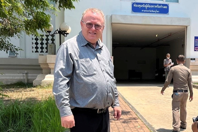 Dosen ilmu politik AS Paul Chambers berdiri di luar kantor polisi di Phitsanulok, Thailand, Selasa (8/4/2025). Foto: AP Photo