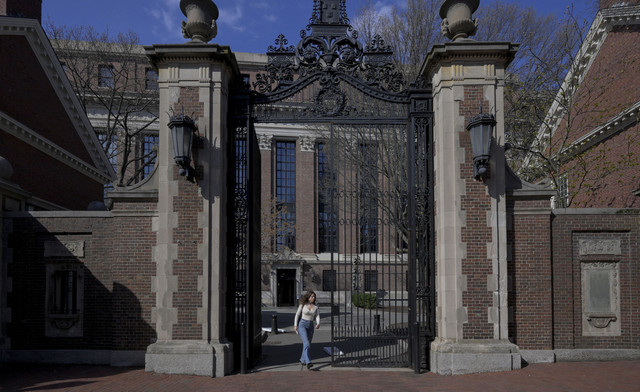 Seorang wanita berjalan di kampus Universitas Harvard di Cambridge, Massachusetts, AS, Selasa (15/4/2025). Foto: Faith Ninivaggi/REUTERS