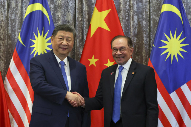 Presiden China Xi Jinping (kiri) berjabat tangan dengan Perdana Menteri Malaysia Anwar (kanan) saat melakukan pertemuan kenegaraan di Istana Nasional, Kuala Lumpur, Malaysia, Rabu (16/4/2025). Foto: Vincent Thian/POOL/AFP