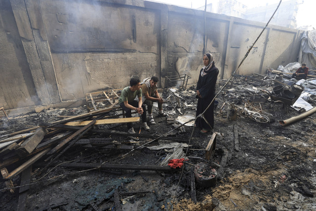 Tiga warga melihat bangunan yang hangus terbakar akibat serangan Israel di salah satu sekolah yang dijadikan penampungan di Gaza, Rabu (23/4/2025). Foto: Dawoud Abu Alkas/REUTERS