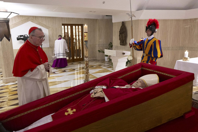 Kardinal Pietro Parolin, sekretaris negara Vatikan, berdiri di dekat jenazah Paus Fransiskus, yang ditempatkan dalam peti jenazah terbuka selama ritual pernyataan kematian di kediaman Santa Marta di Vatikan, Selasa (22/4/2025). Foto: Media Vatikan/via REUTERS