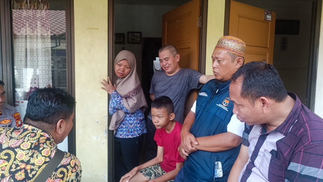 Sosok Cahya Rizki (12), berbaju merah, bersama kedua orang tuanya, Nur (44) dan Supardi (57), saat kepolisian dari Polsek Cinere datang ke rumahnya untuk memastikan keberadaan korban yang telah pulang, Depok, Kamis (25/4). Foto: Thomas Bosco