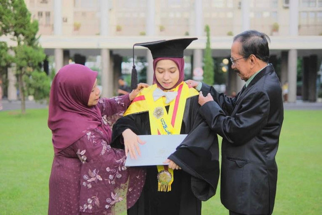 Dewi Agustiningsih, lulusan program doktoral UGM termuda bersama kedua orang tuanya. Foto: Dok. UGM