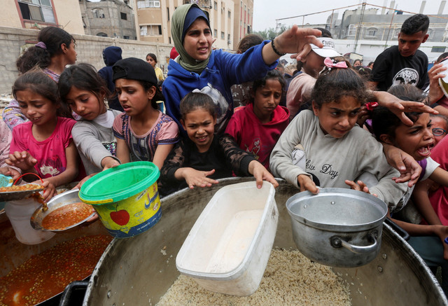 Warga Palestina berkumpul untuk menerima makanan yang dimasak oleh dapur amal di Nuseirat, Jalur Gaza bagian tengah, Selasa (8/4/2025). Foto: Ramadan Abed/REUTERS